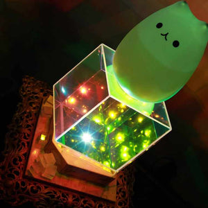 Starfield lamp, with silicone kitten lamp sitting on top of it, illuminated at its lowest setting and appearing to be filled with small stars