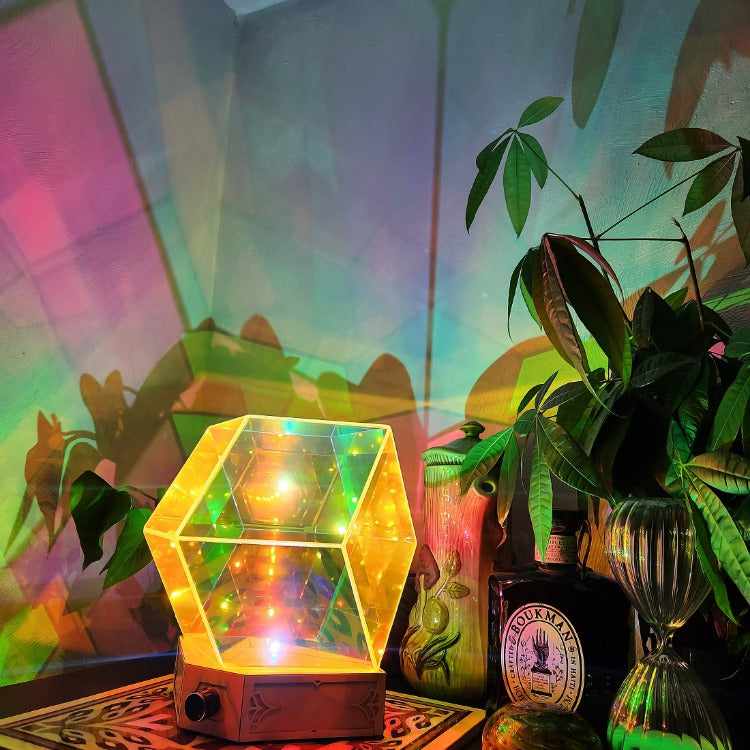 Starfield Lamp, shown illuminated in a home decor setting with a mushroom printed pitcher, houseplants and a glass hourglass and bottle.